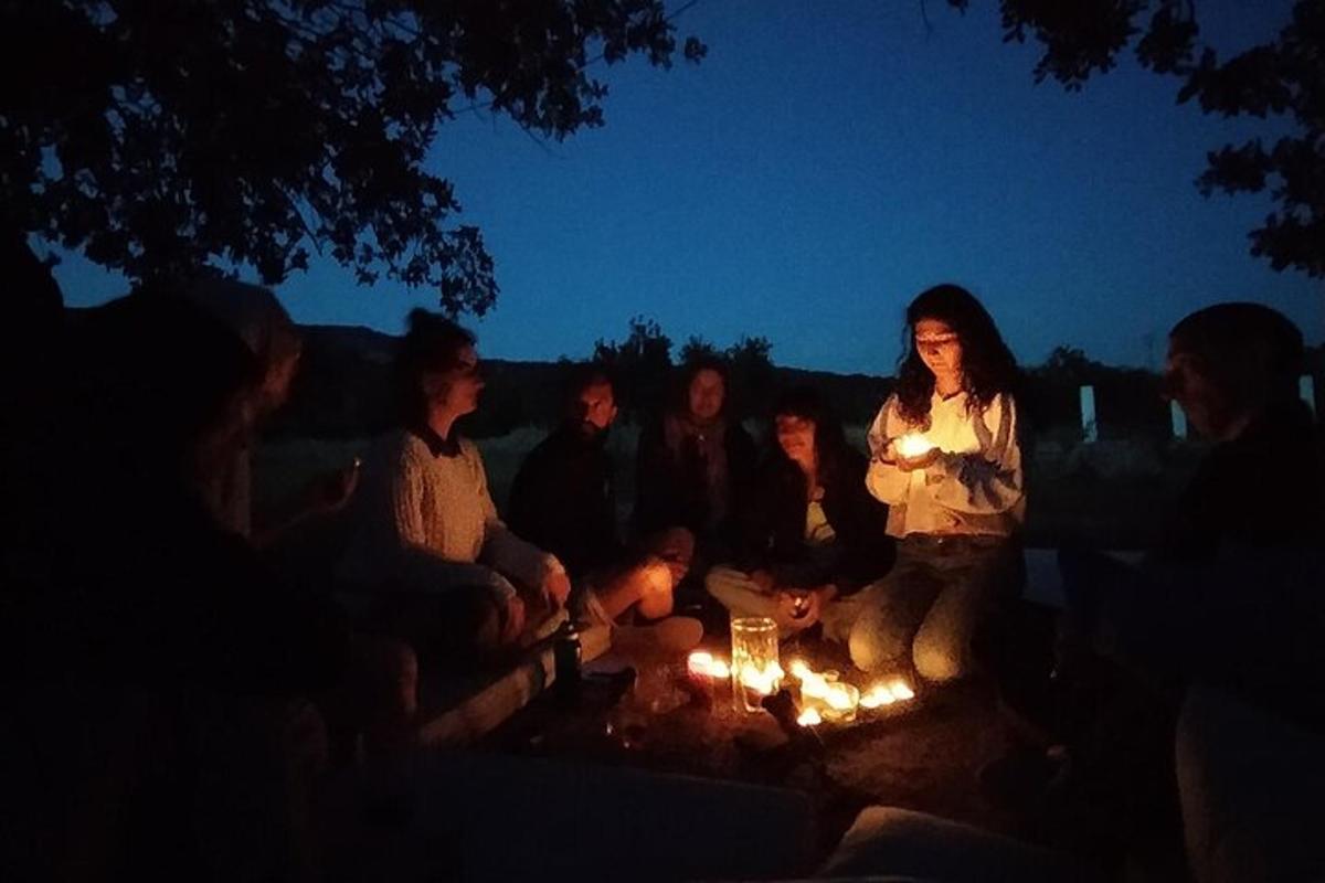 um grupo de pessoas sentadas ao redor de uma fogueira à noite