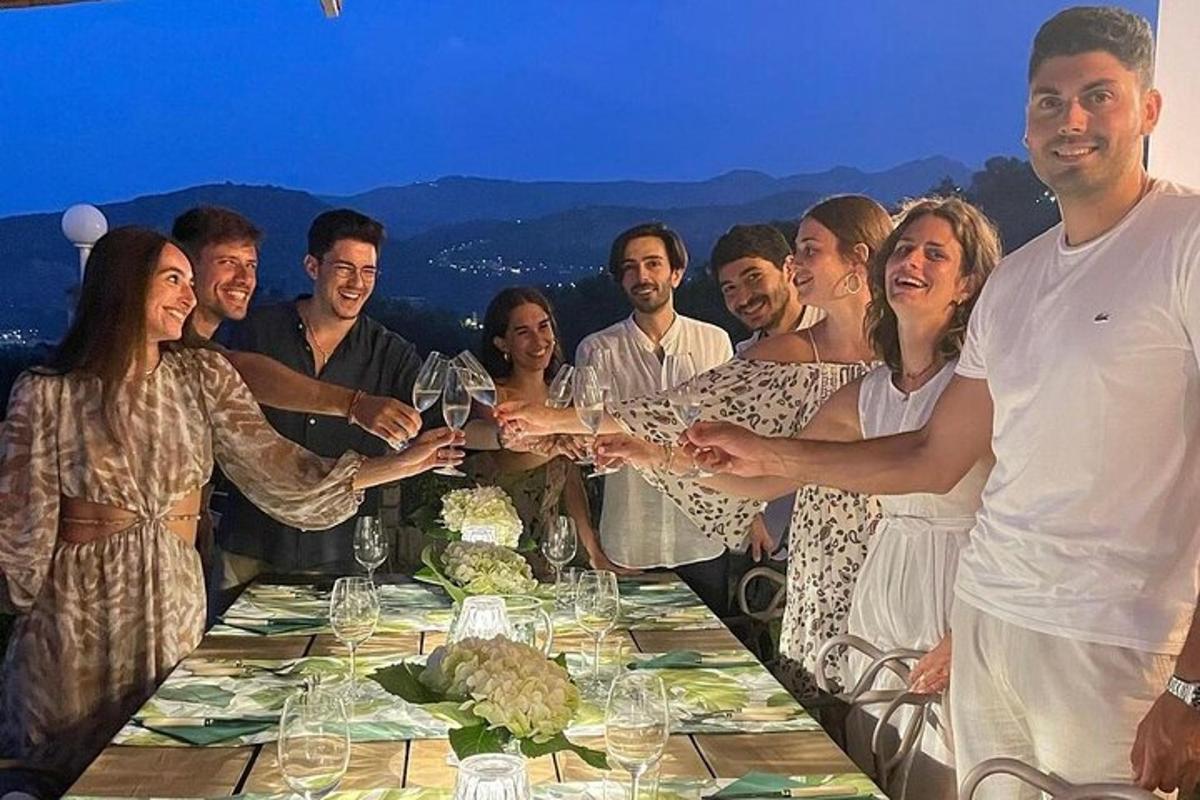 skupina lidí držících u stolu sklenice vína