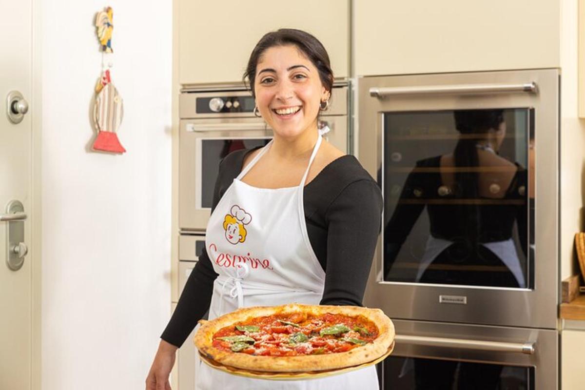 eine Frau hält eine Pizza in einer Küche