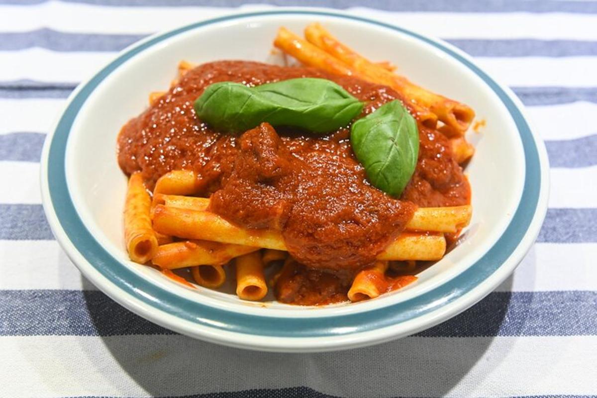 een kom pasta met saus en basilicum op tafel