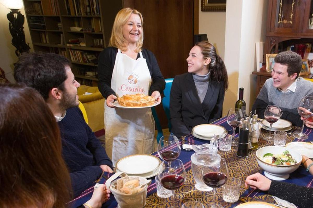 um grupo de pessoas sentadas ao redor de uma mesa com uma mulher segurando um prato de comida