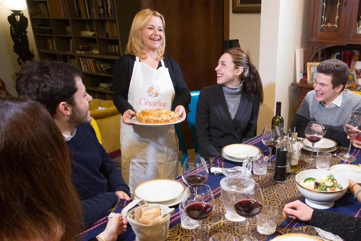 μια ομάδα ανθρώπων που κάθονται γύρω από ένα τραπέζι με μια γυναίκα που κρατά ένα πιάτο φαγητό