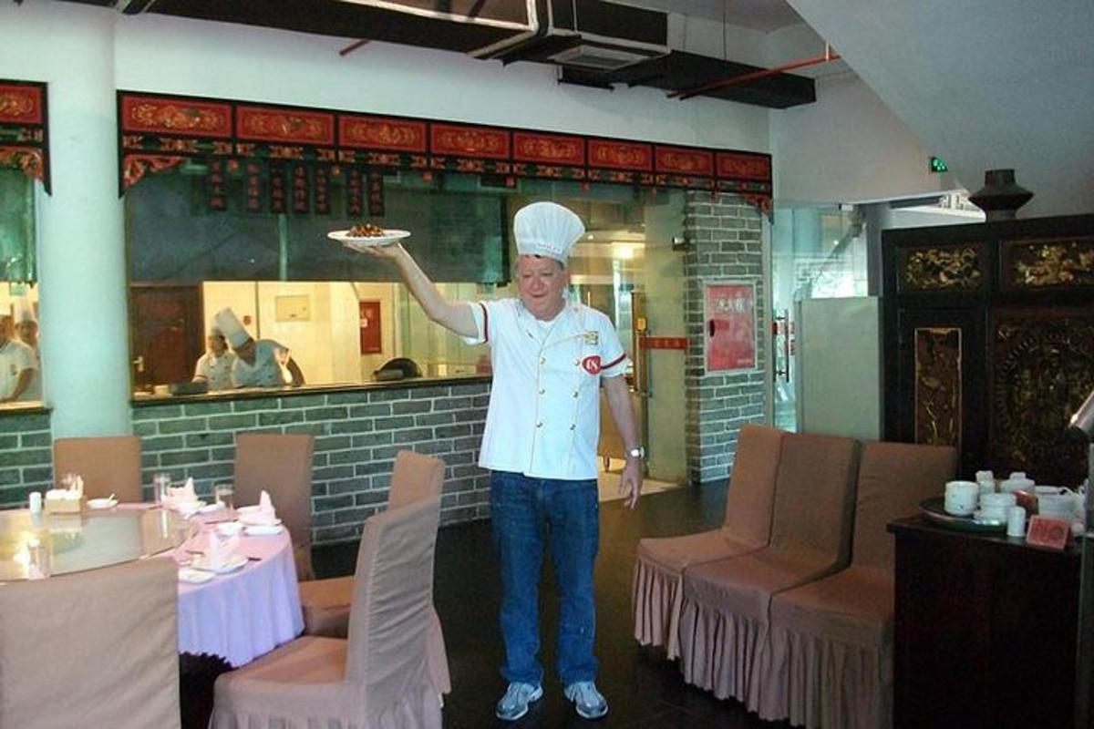 一位厨师站在餐厅里，手里拿着一盘食物