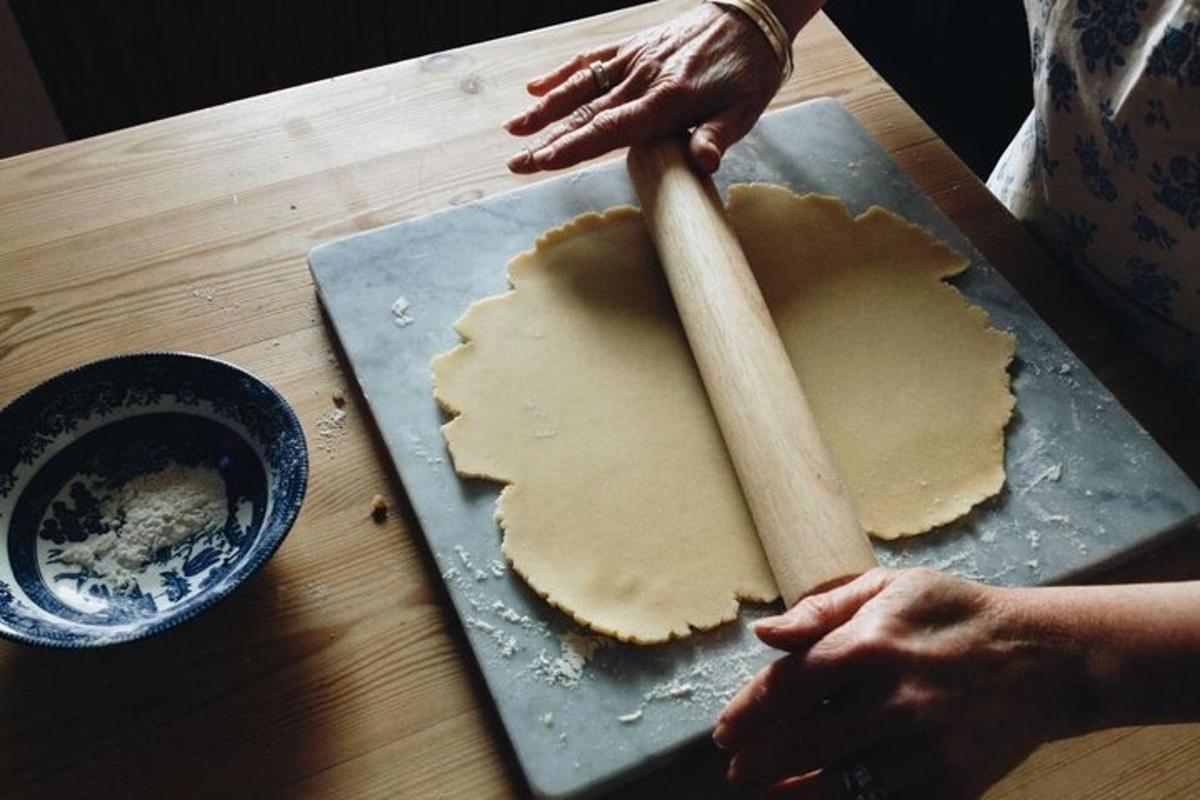 uma pessoa fazendo uma crosta de torta em uma mesa