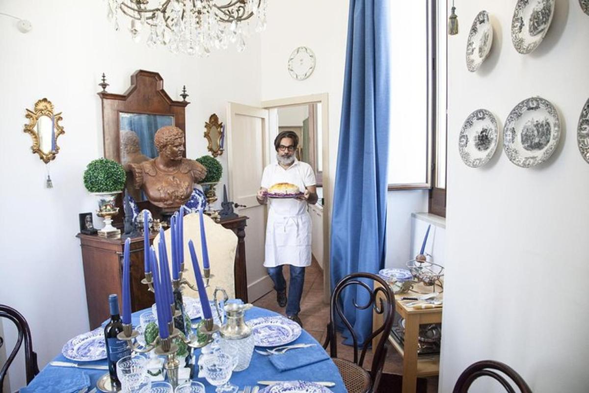 bir masanın olduğu bir odada pasta tutan bir adam