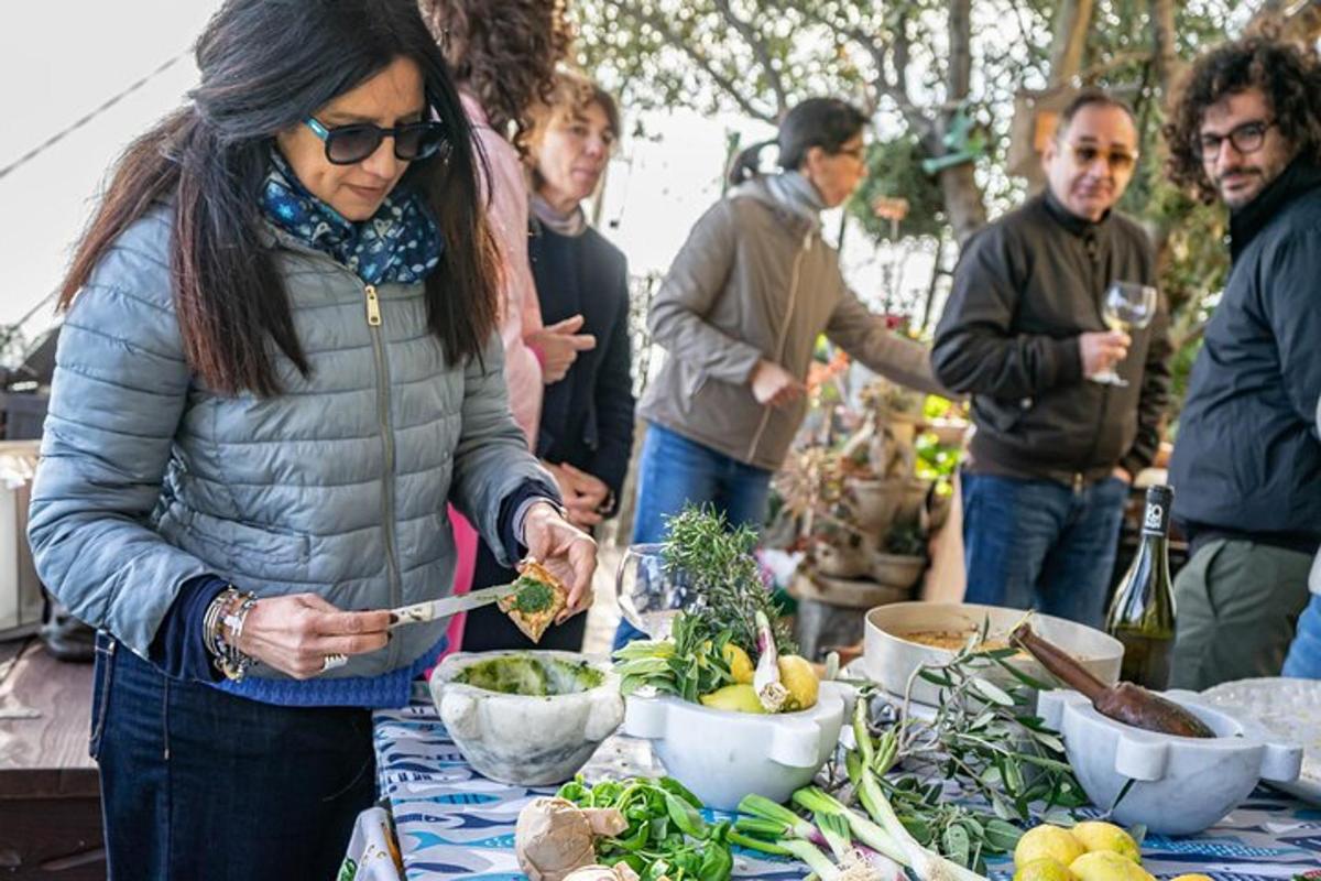 una dona preparant menjar en una taula amb gent al seu voltant