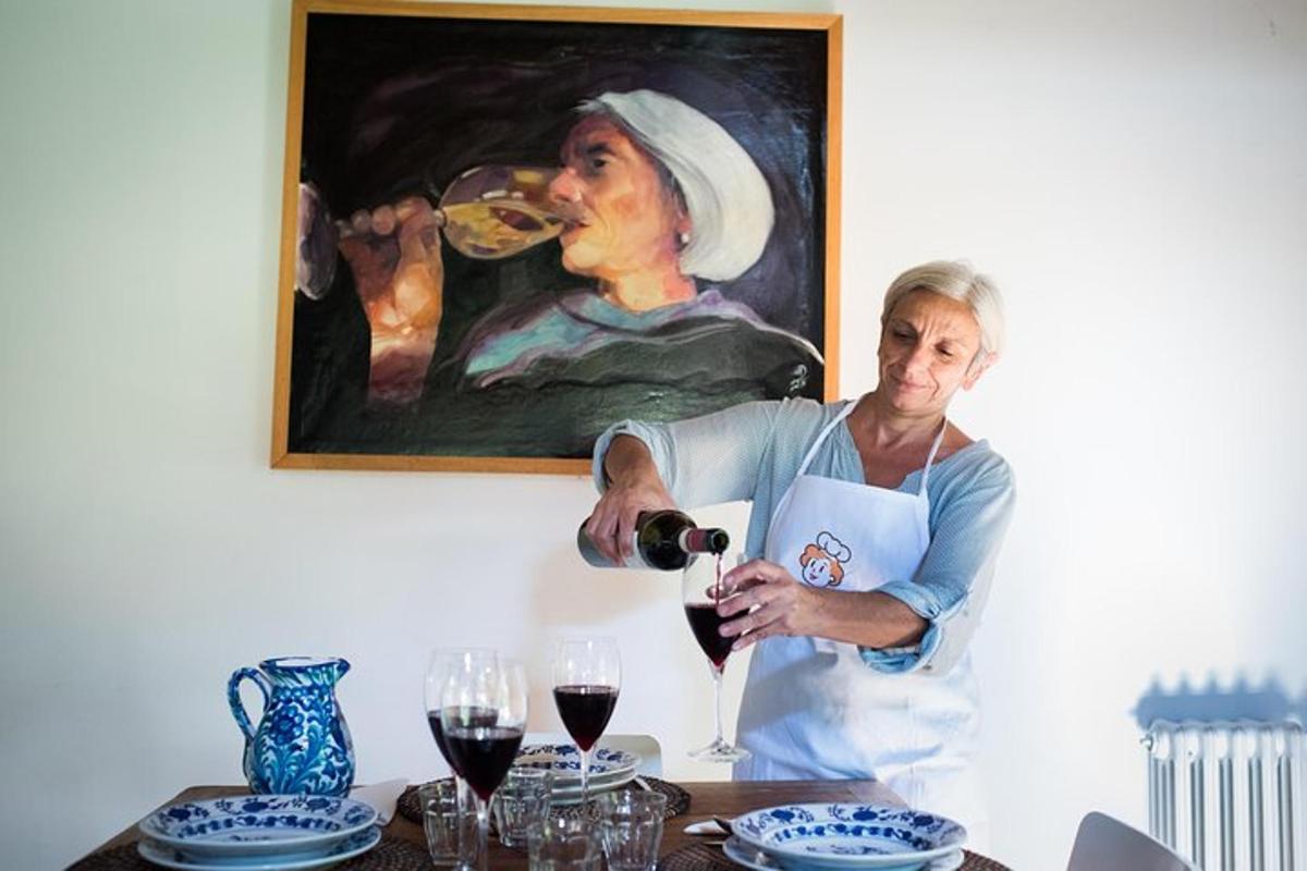 uma mulher servindo uma taça de vinho em frente a uma pintura