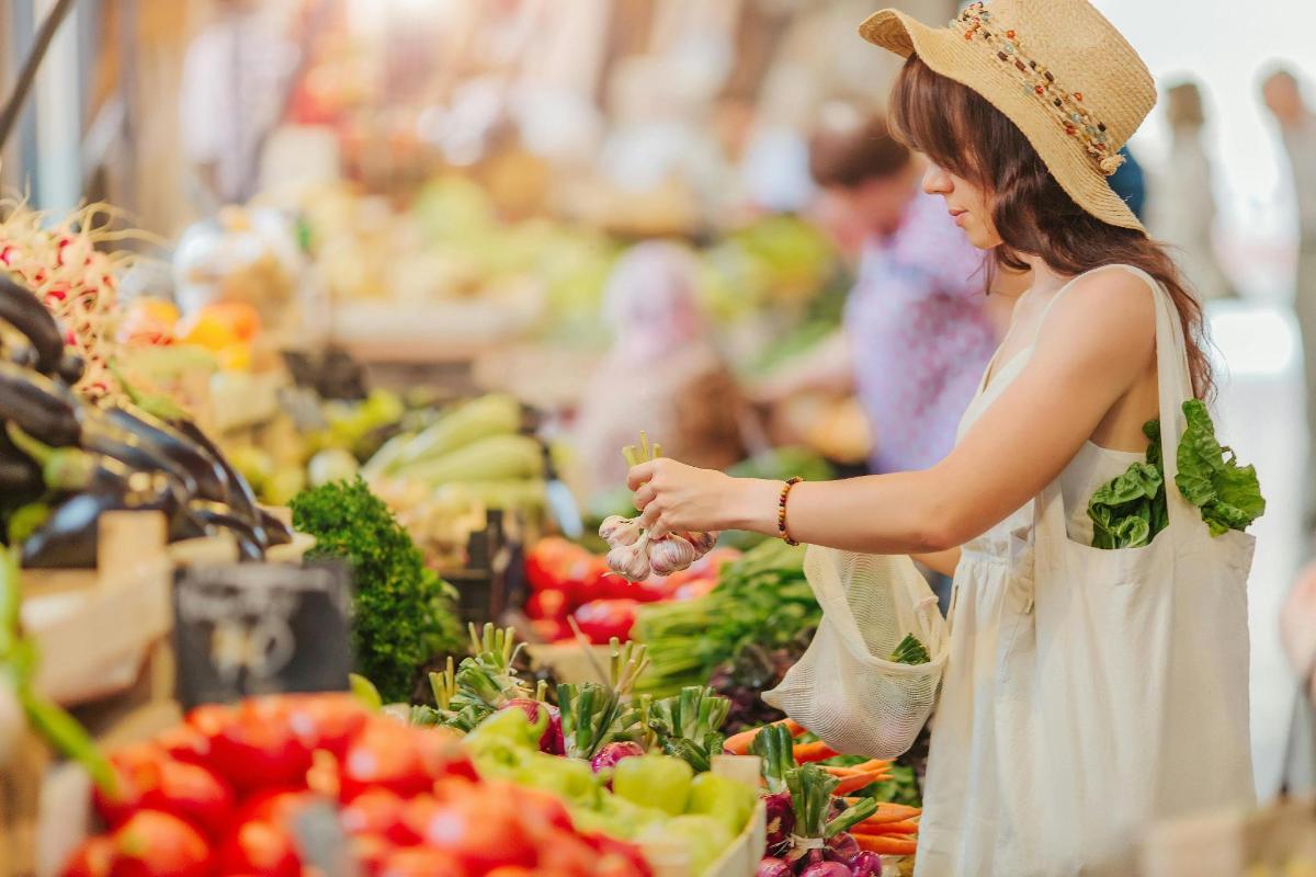 o femeie face cumpărături la piață cu fructe și legume