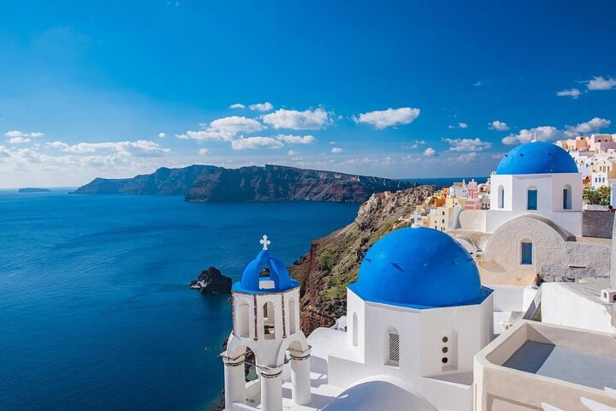 μια ομάδα λευκών κτιρίων με μπλε θόλους και τον ωκεανό