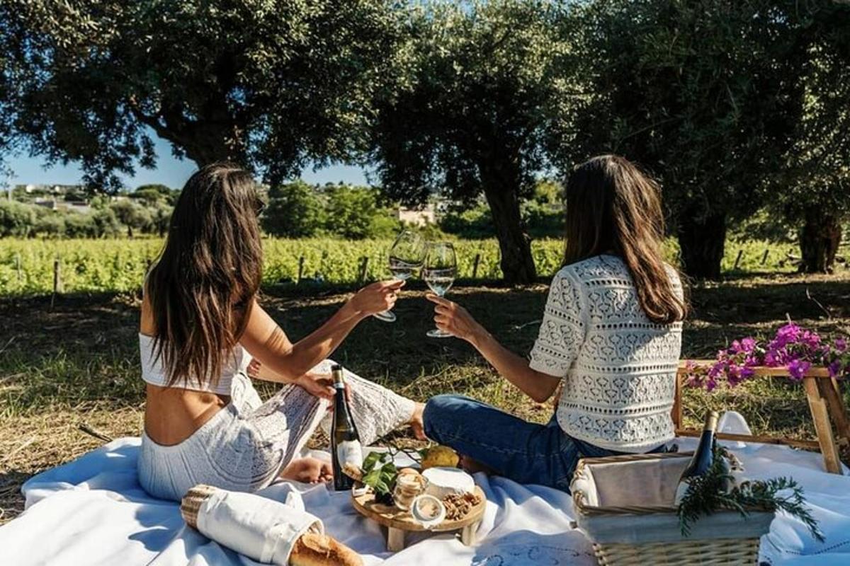 Dos mujeres sentadas sobre una manta sosteniendo copas de vino