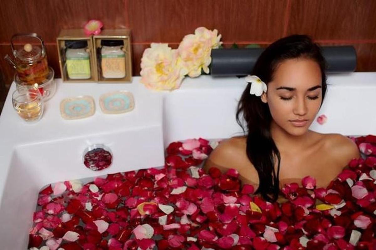 Una mujer tumbada en una bañera cubierta de flores.