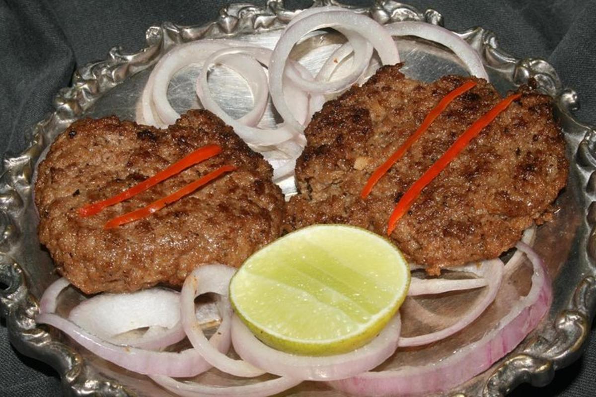 a plate of food with meat and onions and a lime