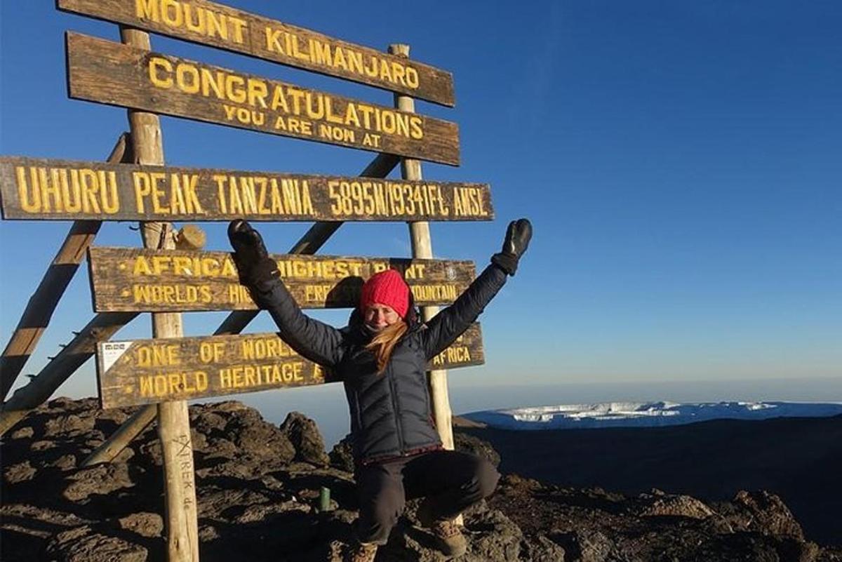 una donna in piedi accanto a un cartello su una montagna