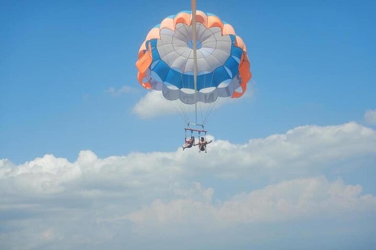 Modrý a oranžový padák letící na obloze