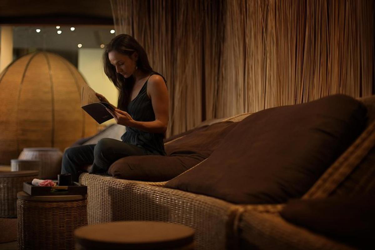 eine Frau, die auf einer Couch sitzt und ein Buch liest