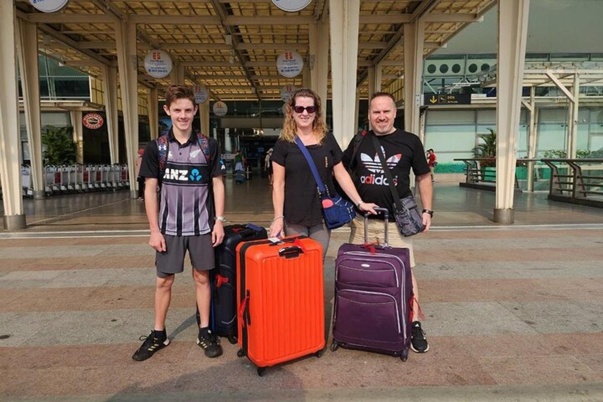 tři lidé stojící se svými zavazadly na letišti