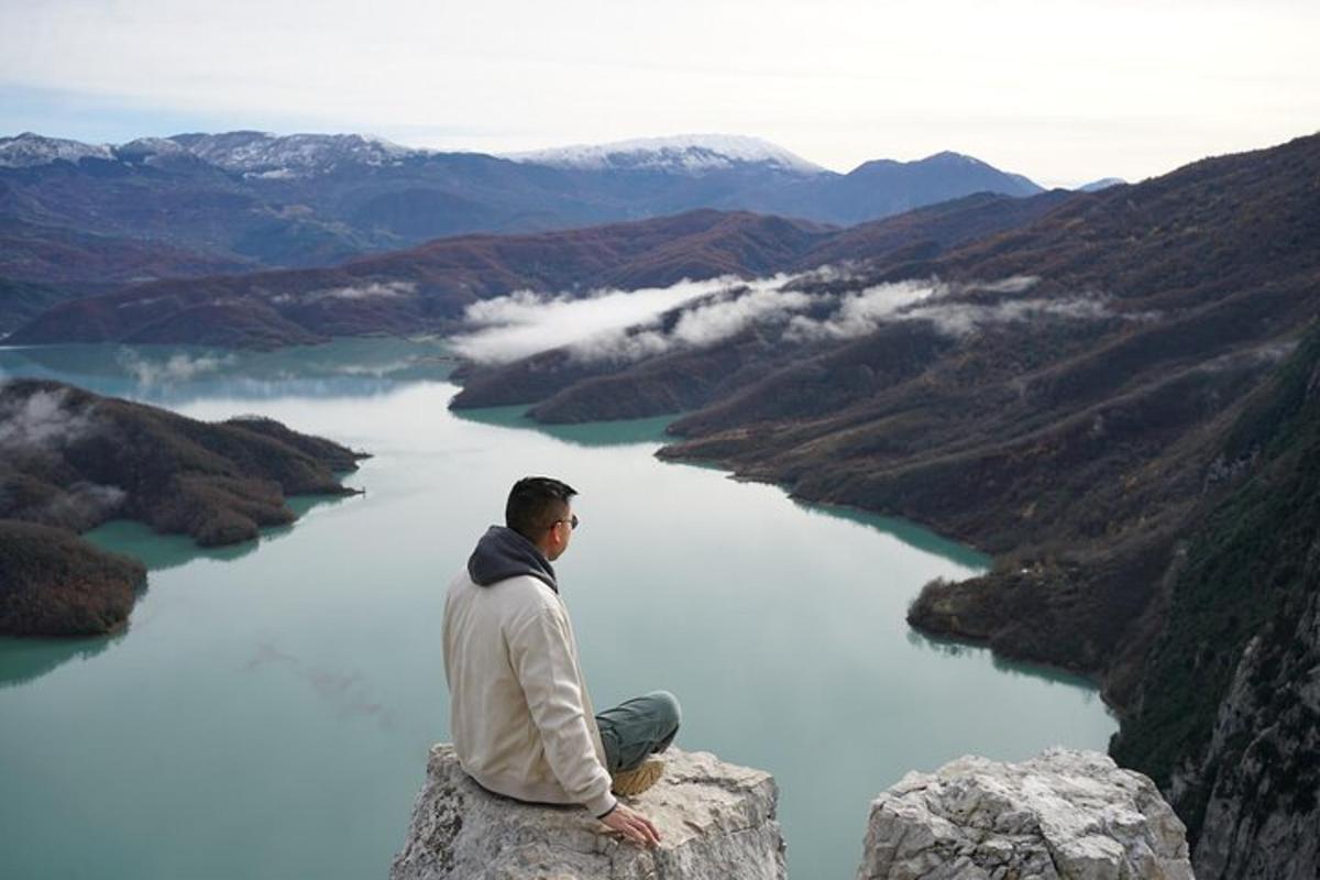 un uomo seduto su una roccia che domina un lago