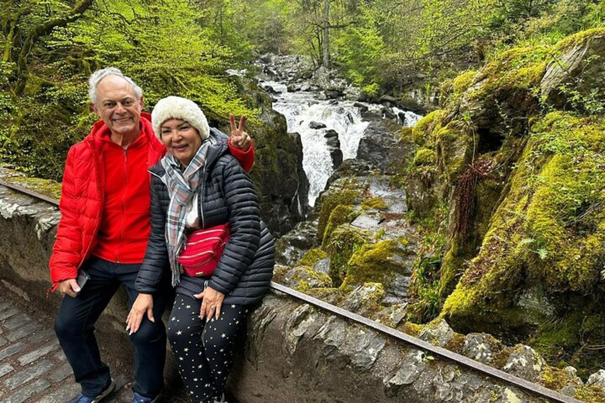 seorang lelaki dan wanita duduk di atas dinding di sebelah air terjun