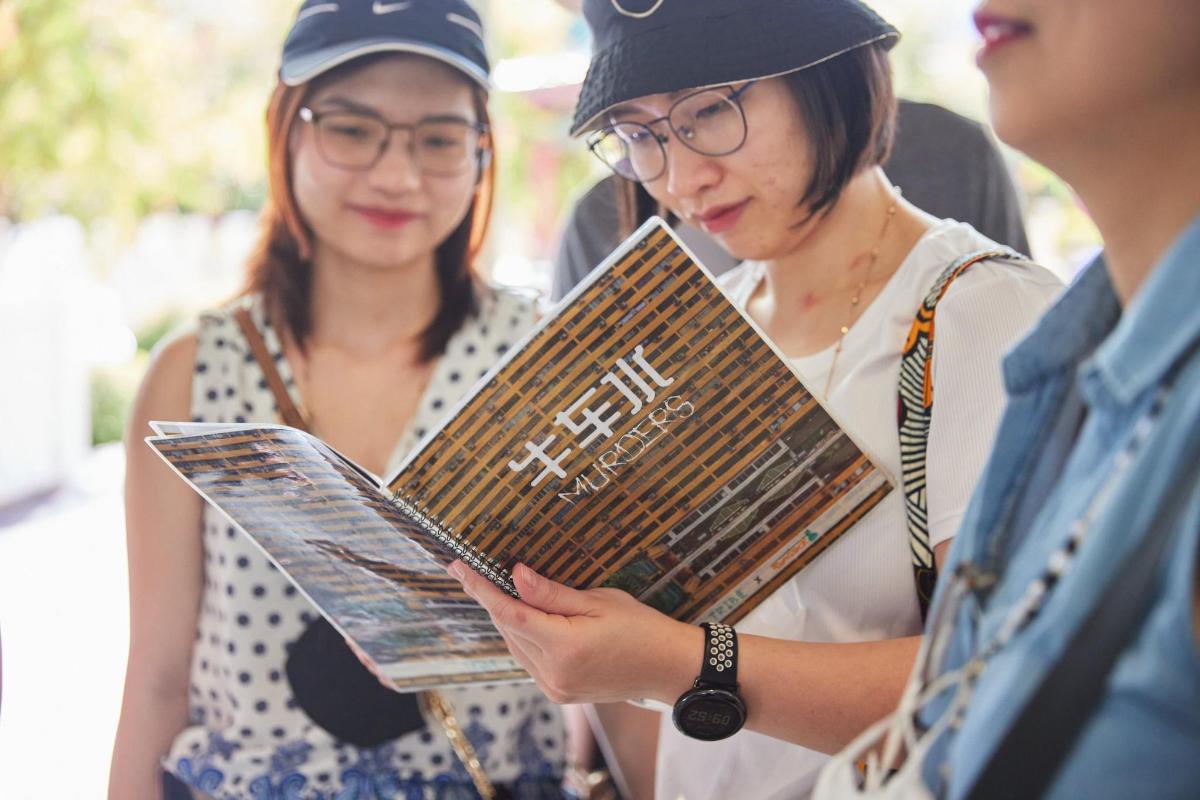 two women are standing and looking at a book