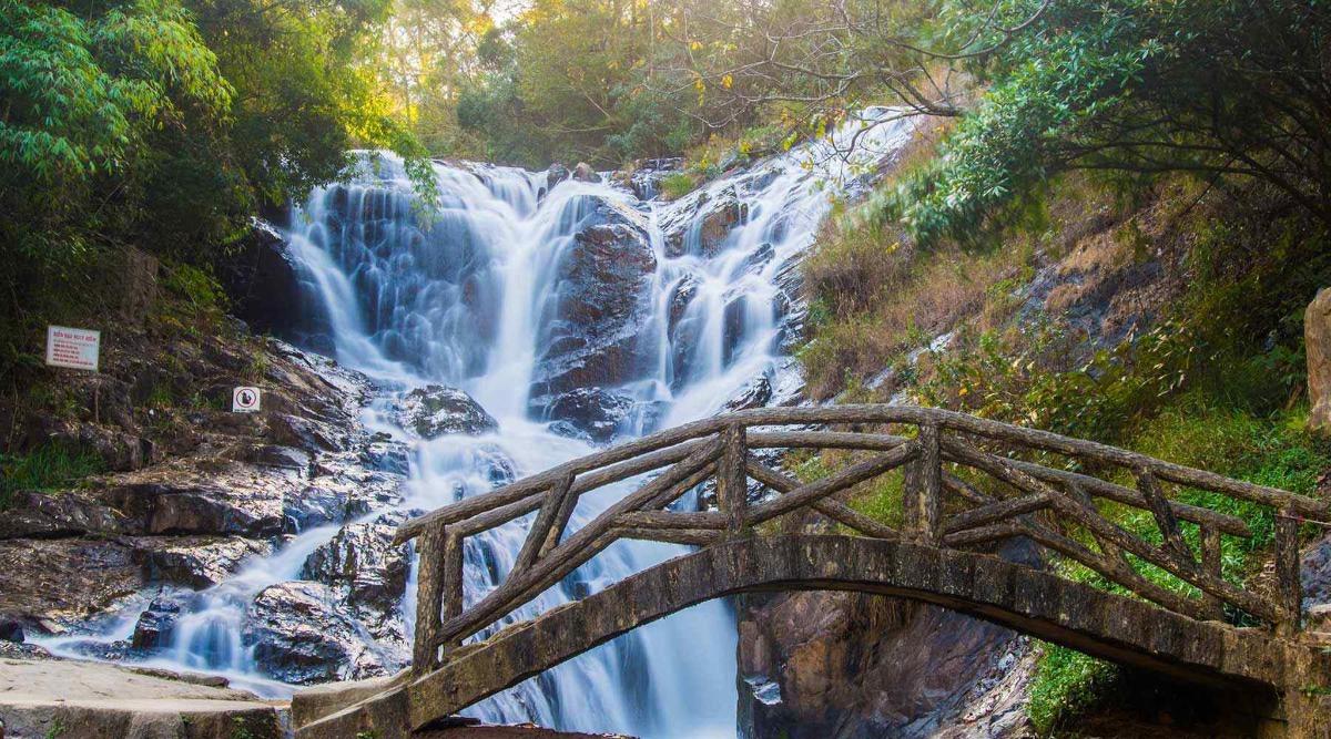 uma ponte de madeira em frente a uma cachoeira