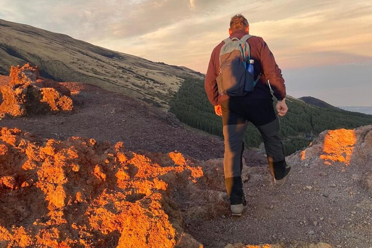 muž s batohem kráčející po vrcholu hory