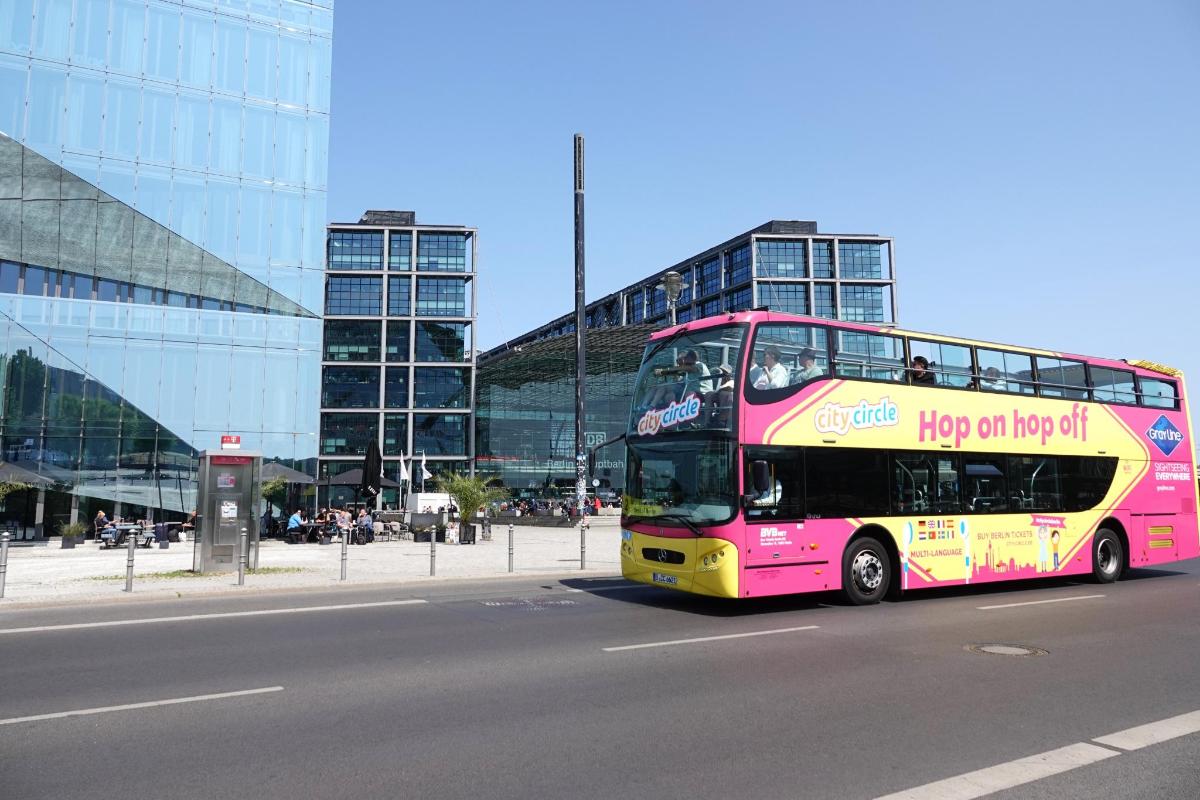 a pink double decker bus driving down a street