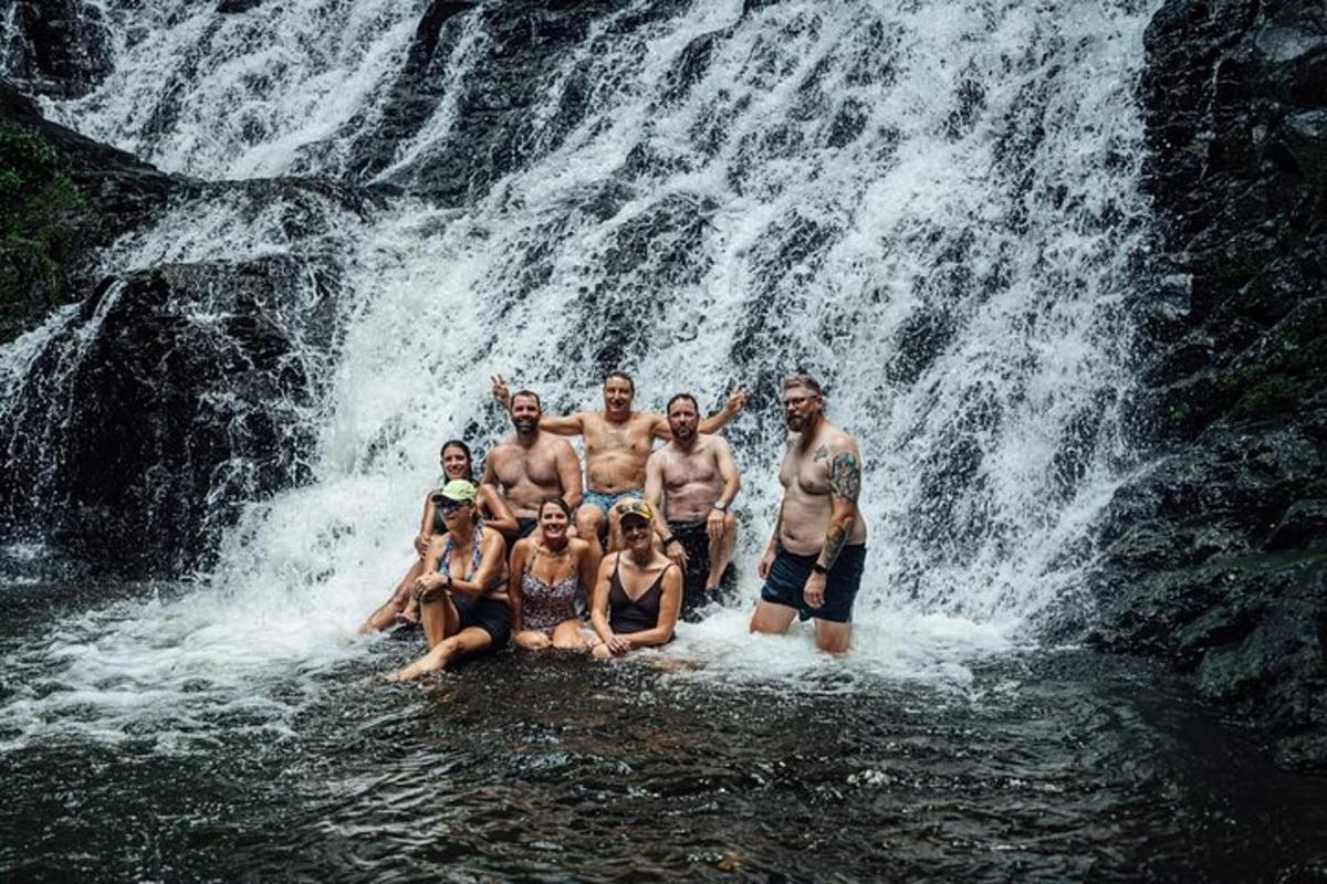 a group of people posing in front of a waterfall