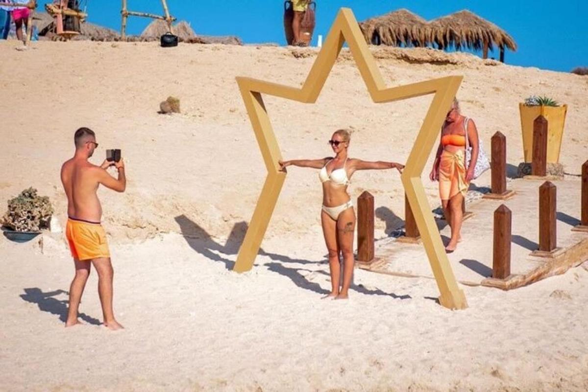 un home fent una foto d'una dona en una estrella a la platja
