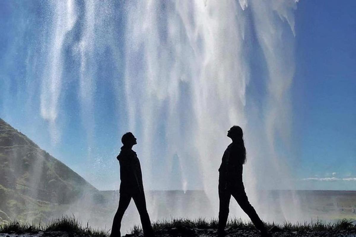 two people walking in front of a waterfall