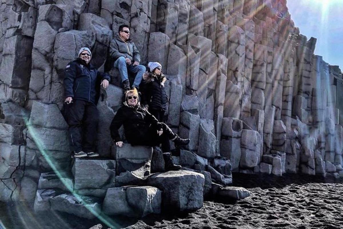 a group of people sitting on rocks next to a stone wall