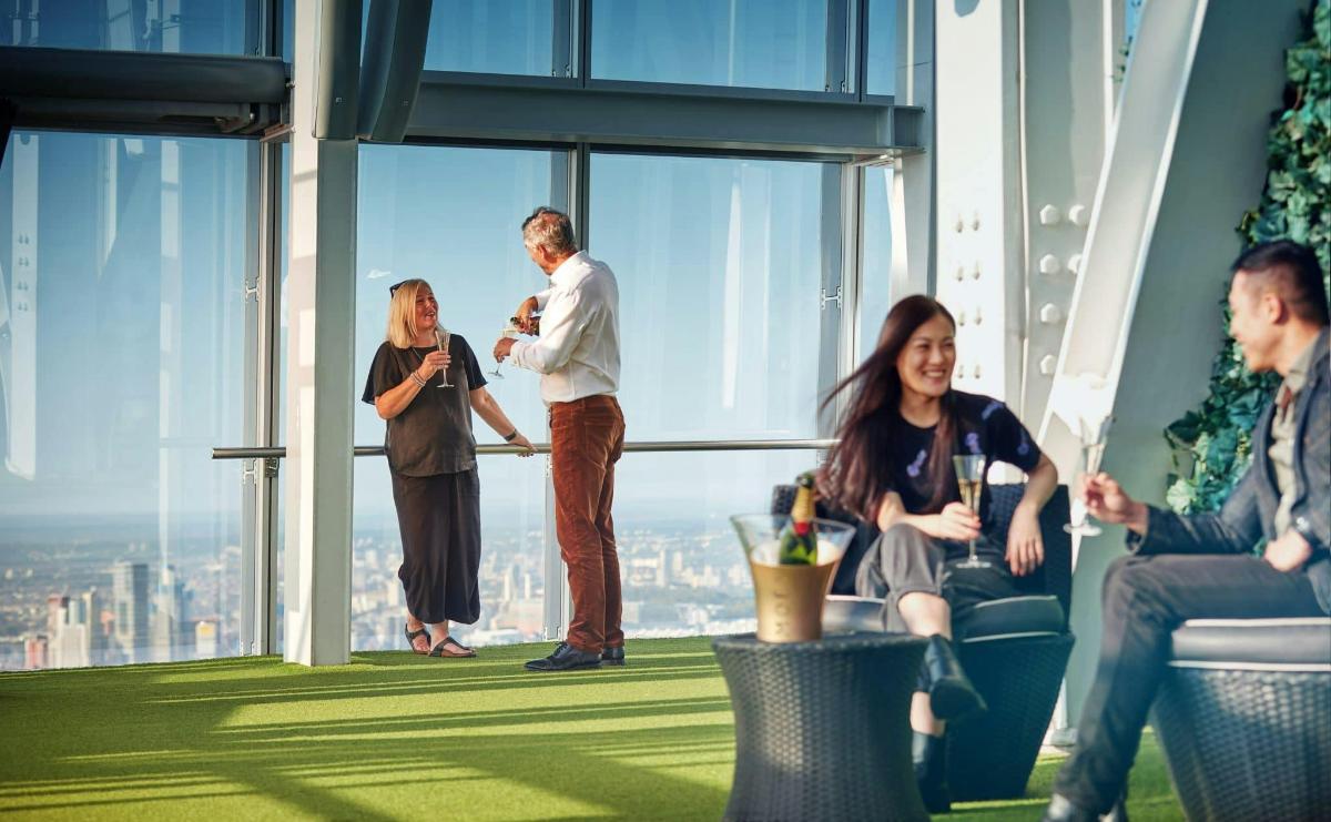 a group of people sitting and standing in a room with windows