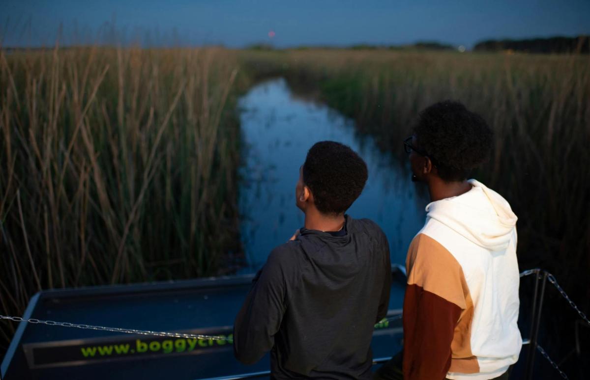 two boys sitting on a boat looking at the water