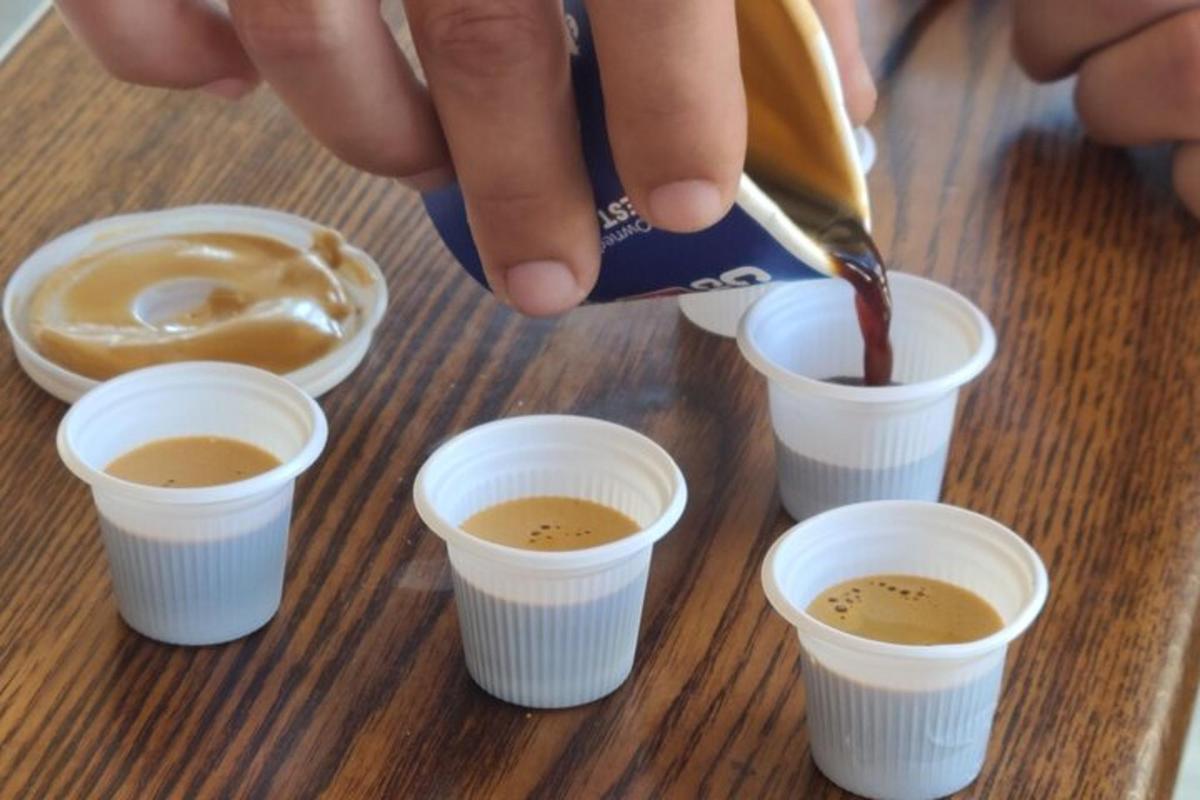 o persoană care toarnă cafea în cești pe o masă