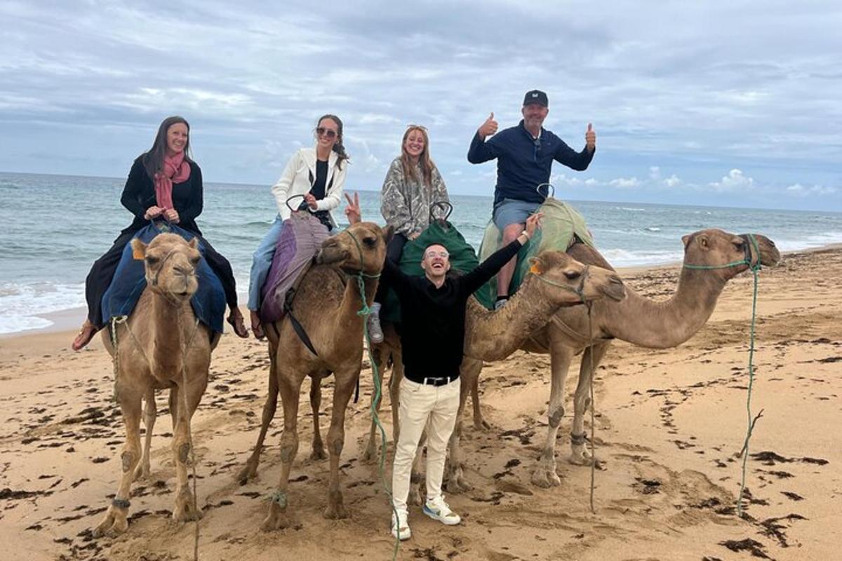 un gruppo di persone a cavallo di cammelli sulla spiaggia
