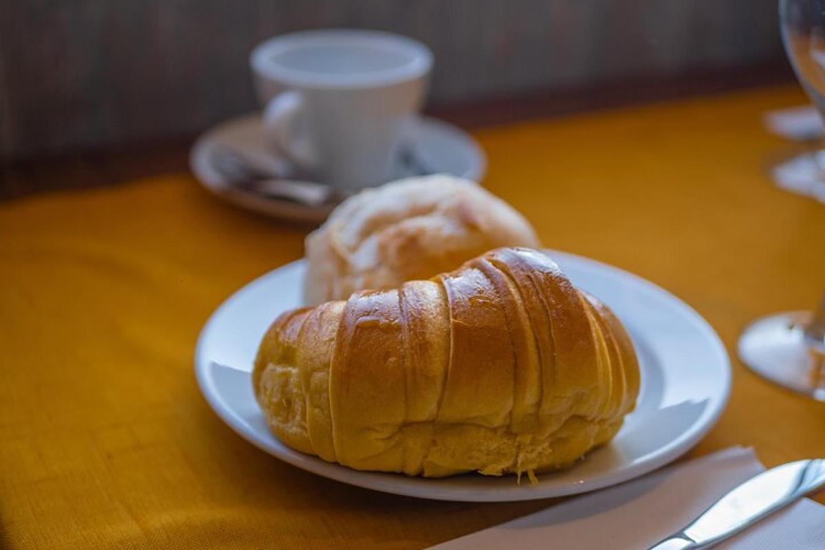 Un plato blanco con un croissant y una taza de café.