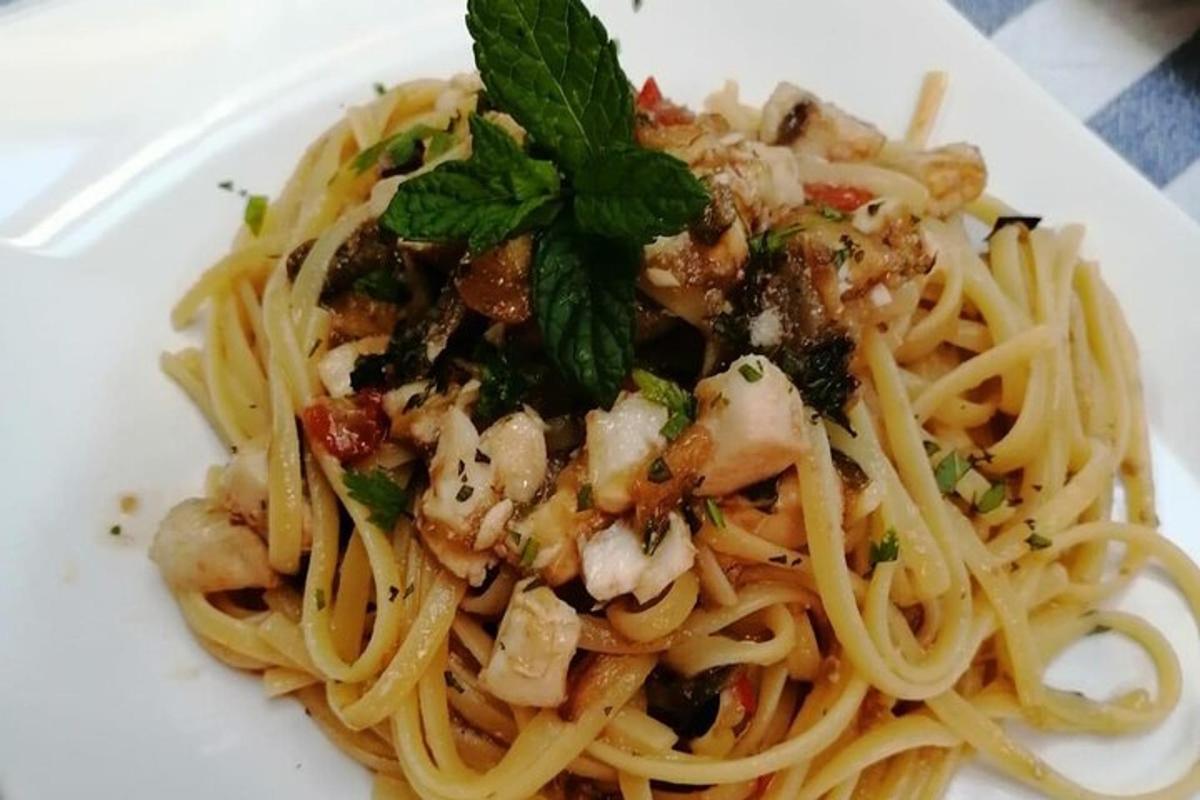en tallerken med pasta med reker og grønn pynt