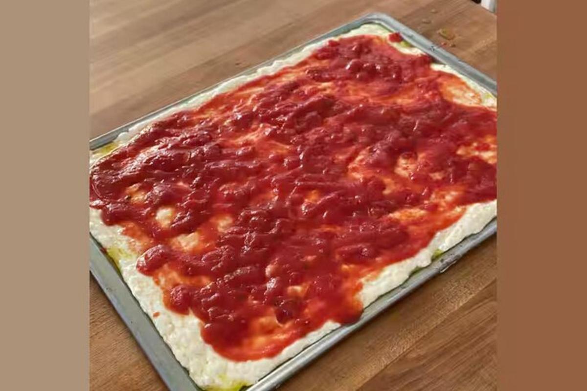 een pizza met saus in een pan op tafel