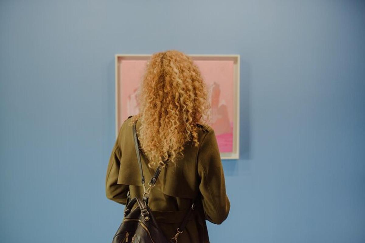 a woman with long curly hair standing in front of a painting