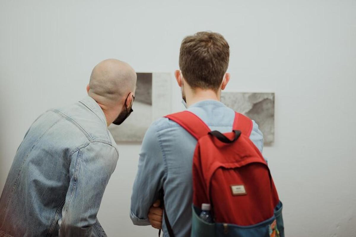 two men looking at a painting in an art gallery