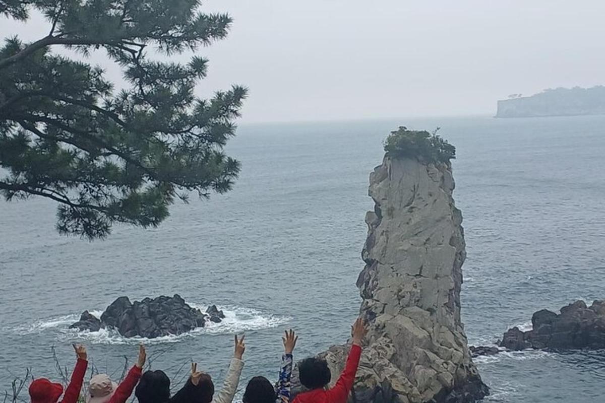 un gruppo di persone in piedi attorno a una roccia in riva all'oceano