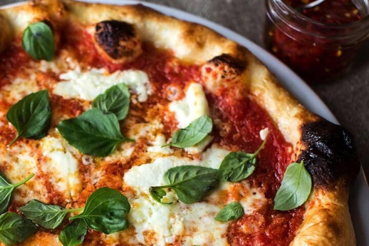 una pizza con foglie di basilico su un piatto