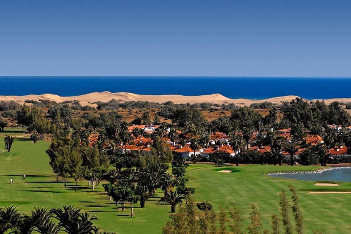 padang golf dengan resort dan bukit pasir di latar belakang