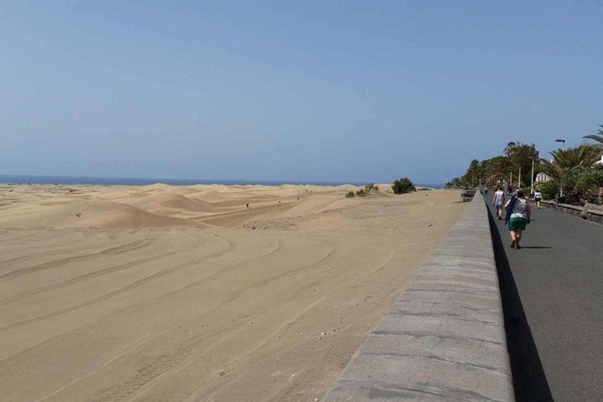 uma praia com pessoas caminhando em uma trilha na areia