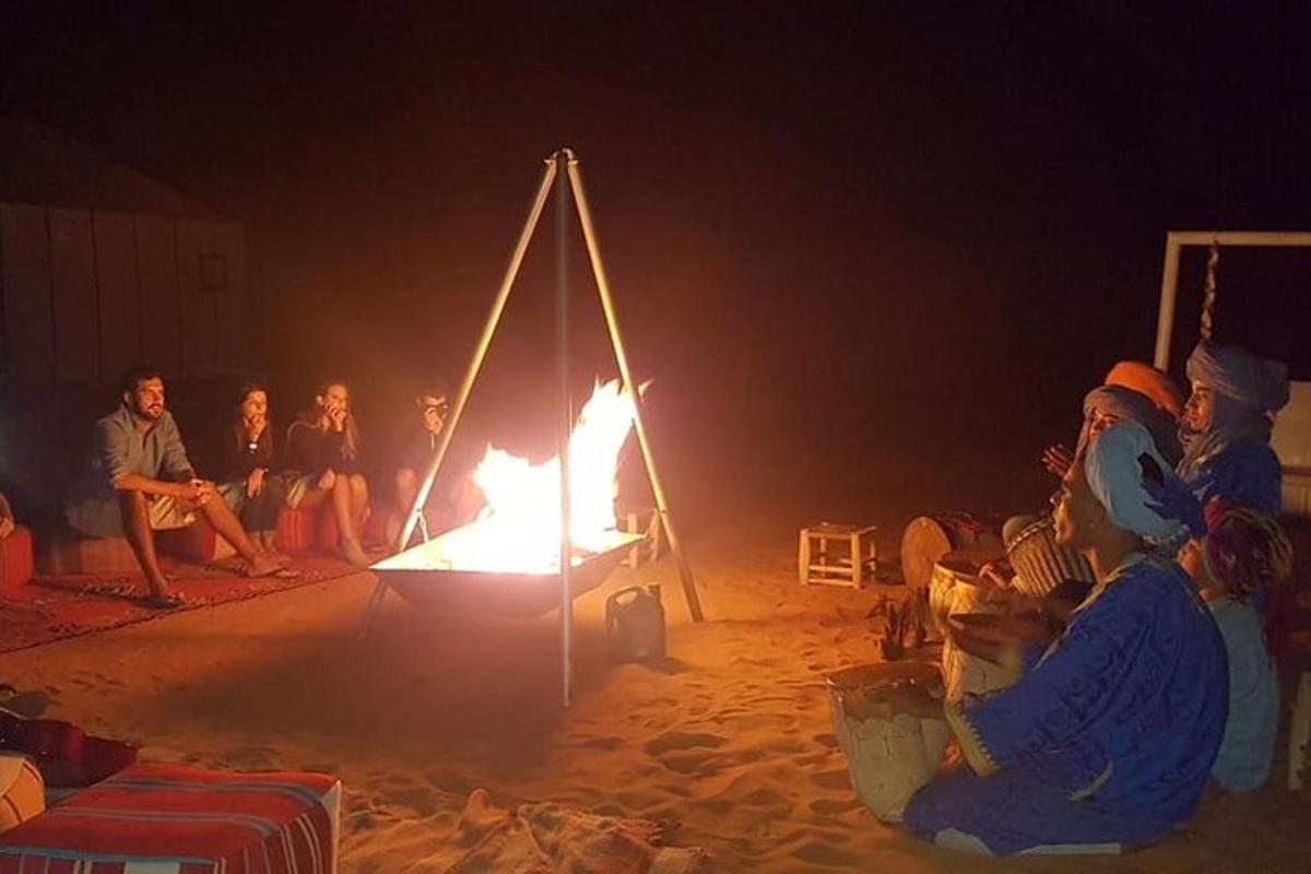 Grupa ludzi siedząca wokół ogniska na plaży