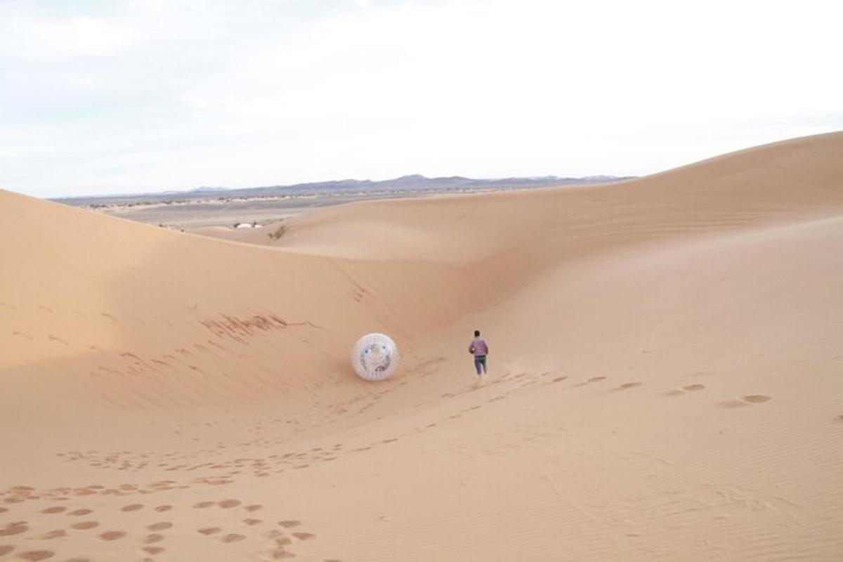 un uomo che cammina nel deserto con un pallone da calcio