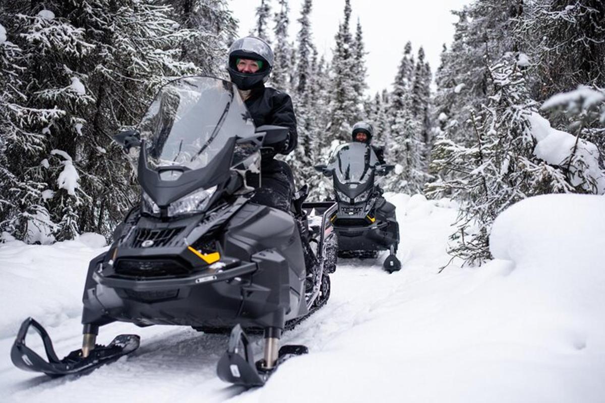 en man som står bredvid en snöskoter i snön