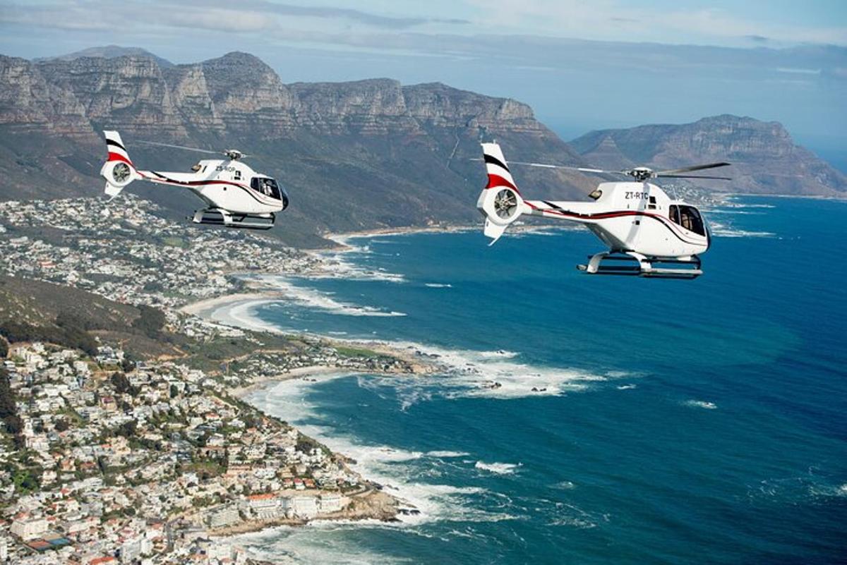 dos helicòpters blancs volant sobre l'oceà a prop de la platja