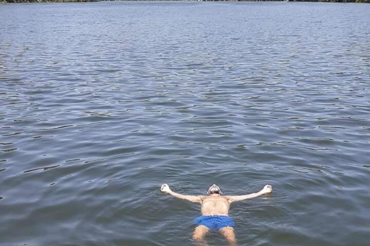 un uomo che nuota in un lago con le braccia tese