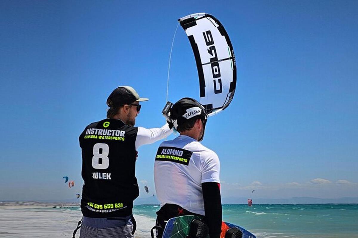 two people standing on the beach with a kite