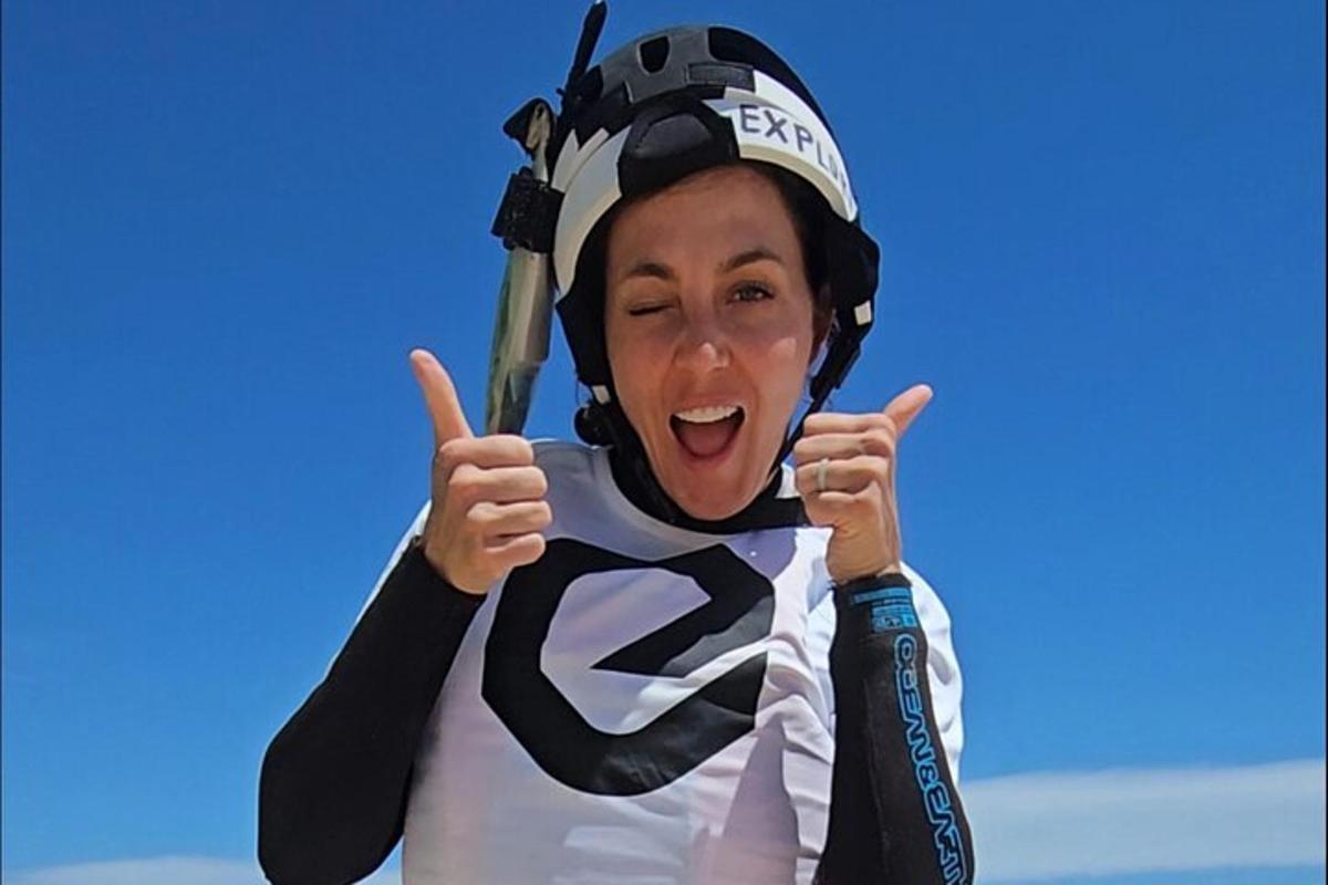a woman wearing a helmet and giving the thumbs up